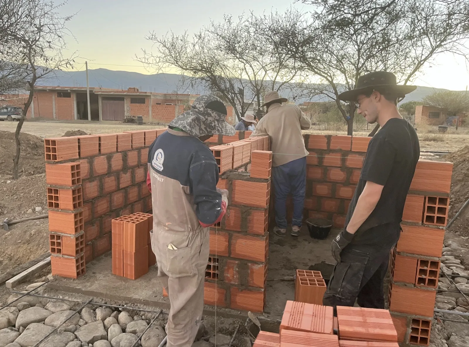 Team members and local masons laying brick walls for the public restroom