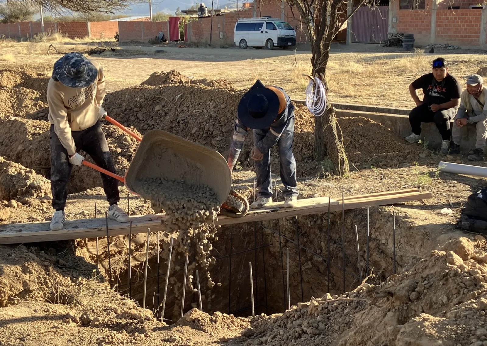 Workers barrowing concrete into the septic tank excavation