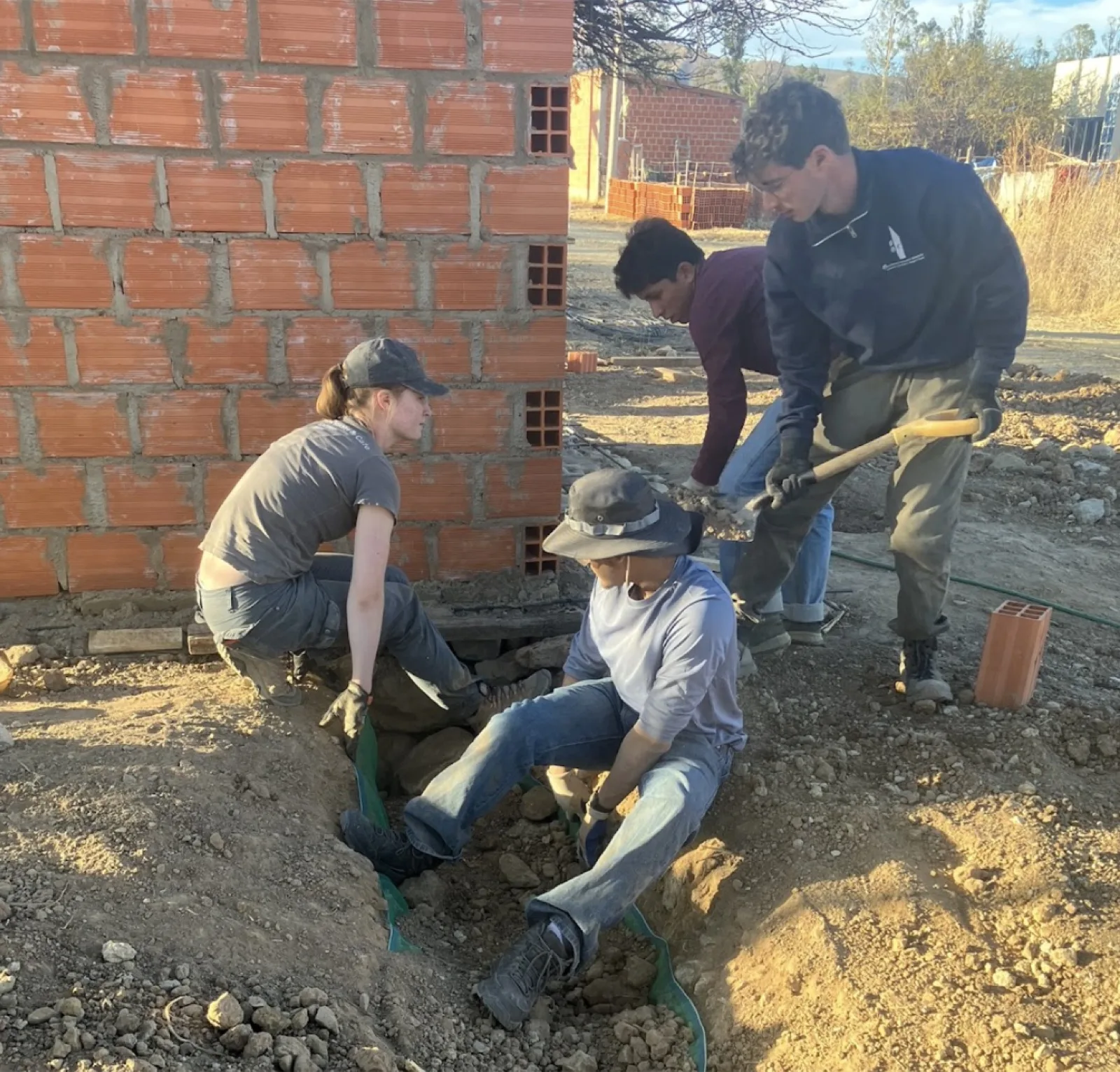 Team members setting pipe alongside the brick restroom structure