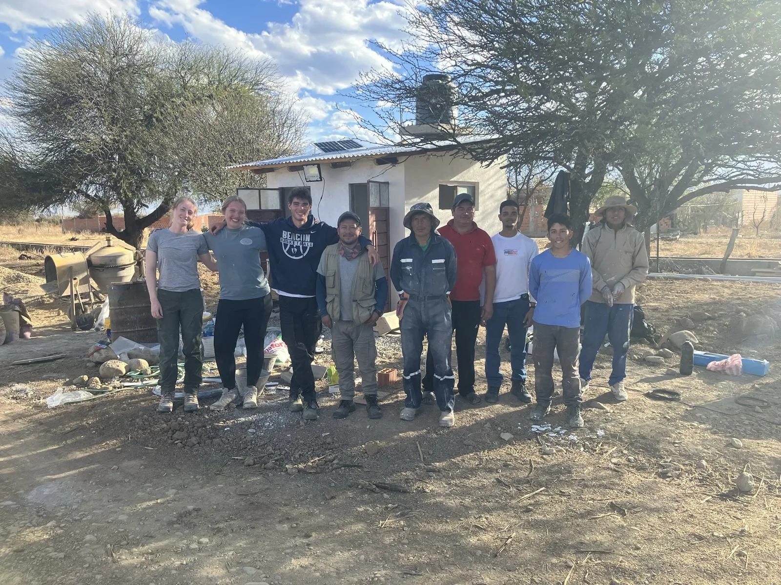 The 2026 implementation team with local masons outside the finished restroom