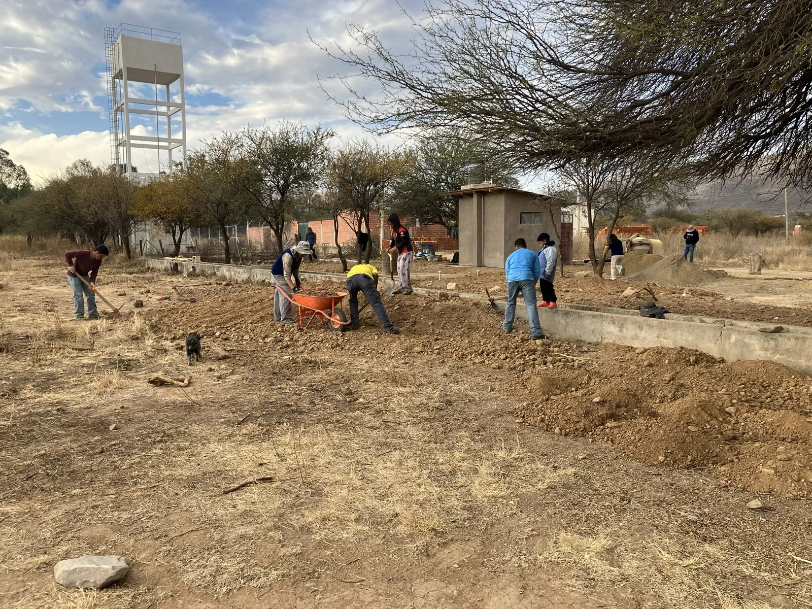 Crew digging by hand with the new water tower behind them